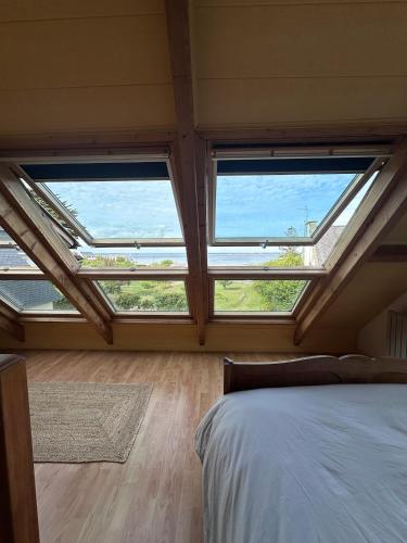 a bedroom with two large windows and a bed at La Petite Maison Bénance in Sarzeau