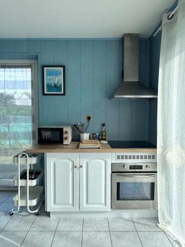 a kitchen with blue walls and a stove top oven at La Petite Maison Bénance in Sarzeau