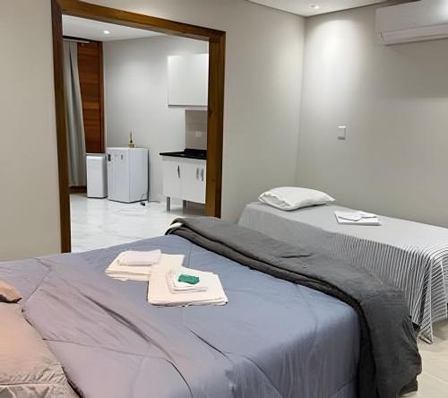 two beds in a room with a kitchen in the background at Lady Estúdio - Hotel + café em Extrema MG in Extrema