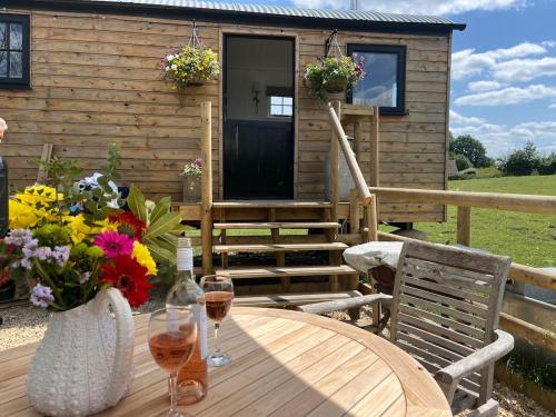 a wooden table with wine glasses and flowers on a cabin at Wiltshire Weavers Hut in Chippenham