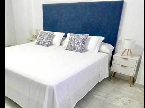 a bedroom with two beds with white sheets and a blue wall at MI CAPRICHO BEACHFRONT 410 - Apartment with terrace and private garden by the sea in Mijas Costa