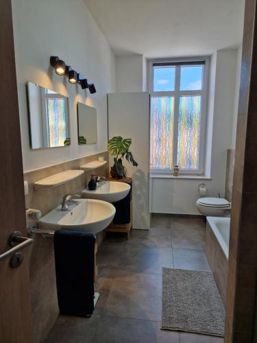 a bathroom with two sinks and a tub and a toilet at Echternach Center Charming Apartment in Echternach