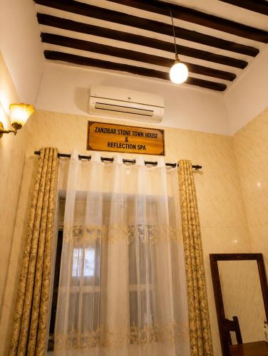 a room with a window with curtains and a sign at Zanzibar stone town house in Zanzibar City