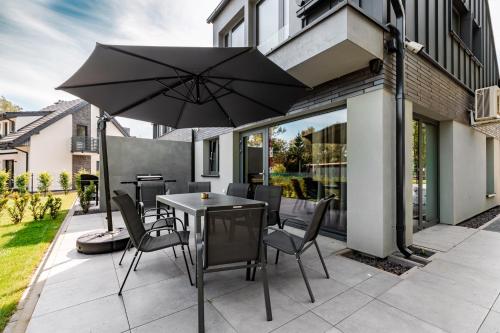 a table and chairs with an umbrella on a patio at Marina Dziwnów Premium Haus 2 in Dziwnów