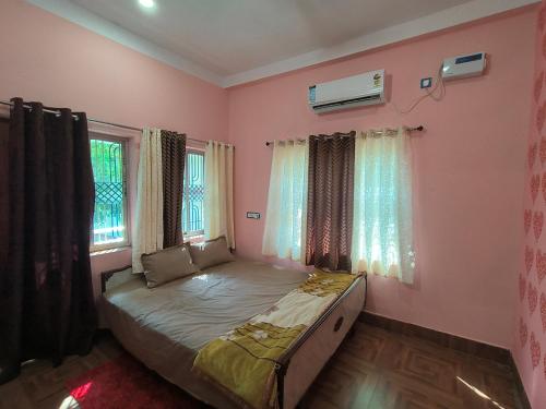 a bedroom with a bed with pink walls and windows at Bhakti Suite in Deoghar