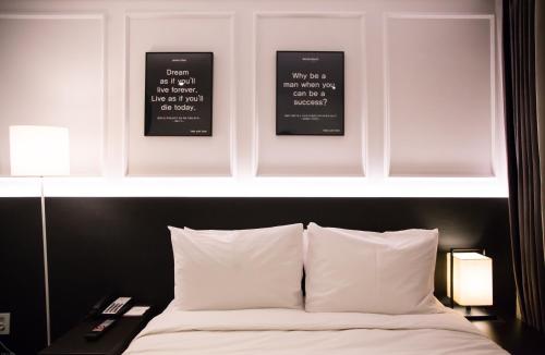 a bedroom with two pictures above a bed with white pillows at Vella Suite Hotel in Suwon