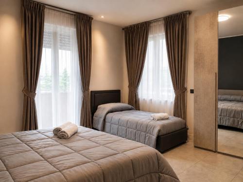 ein Schlafzimmer mit zwei Betten und einem Spiegel in der Unterkunft Hotel Genesis in Vignola