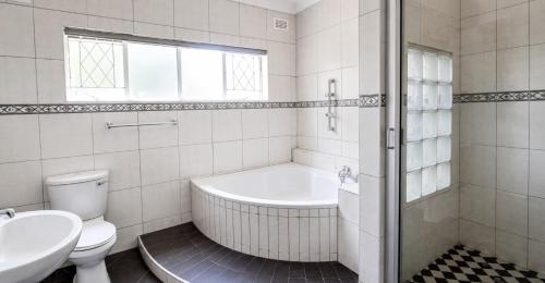 a bathroom with a tub and a toilet and a sink at The Vine House in Harare