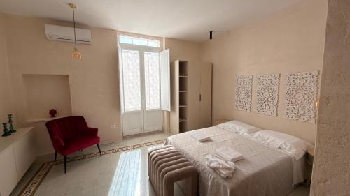 a bedroom with a bed and a red chair at B&B Casa di Leo in Brindisi