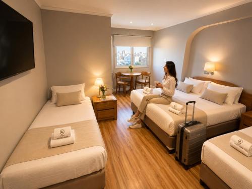 a woman sitting in a hotel room with two beds at Goya Hotel in Buenos Aires