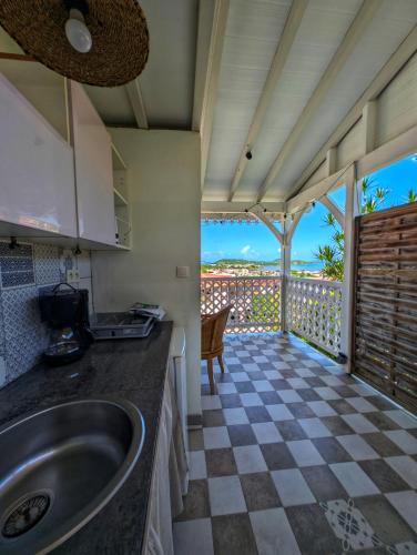 a kitchen with a sink and a balcony with a view at Studio Frangipani dans Villa Fleurs des Iles in Le Vauclin