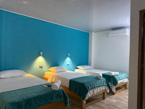 two beds in a room with a blue wall at Hotel Sunset Beach in Cartagena de Indias