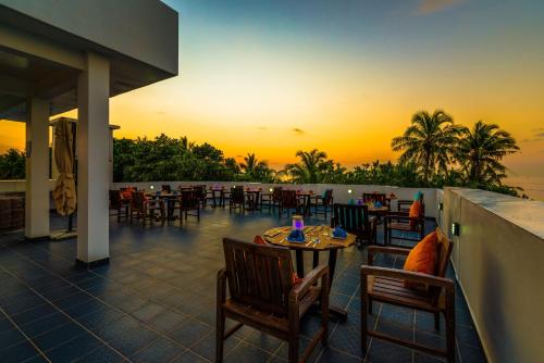 a patio with tables and chairs with a sunset in the background at Boutique Beach All Inclusive Diving Hotel in Dhigurah