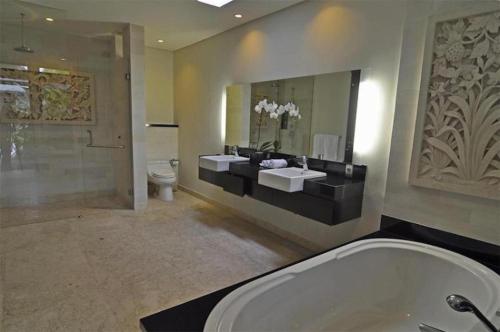 a bathroom with two sinks and a toilet and a mirror at Villa Kejora 10 in Sanur