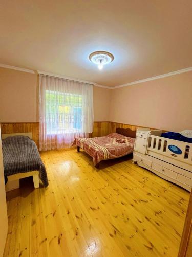 a bedroom with two beds and a window and wooden floors at Sweet home in Lerik