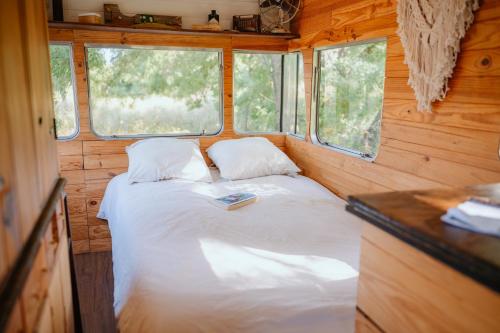 a small bedroom with a bed and two windows at Olívia, Caravana Vintage, Castelo de Vide in Castelo de Vide