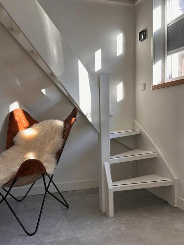 a chair in a room with a staircase at The Lighthouse Cabin in Noordwijk