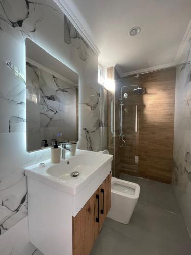 a white bathroom with a sink and a toilet at Vila JONI in Berat