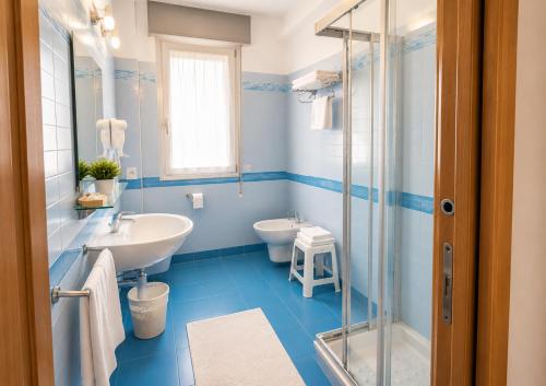 a blue bathroom with a sink and a toilet at Hotel Bertha Fronte Mare in Lido di Jesolo