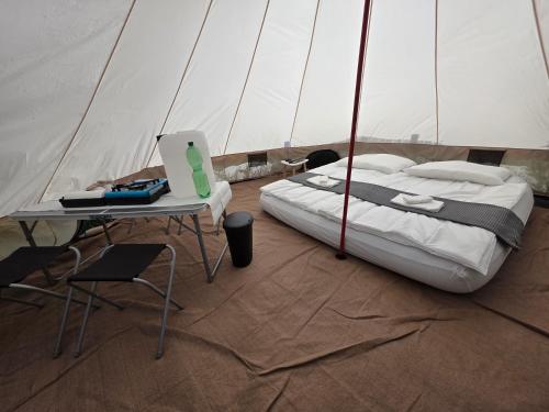 a bedroom with a bed and a table with a laptop at Acorn Pool Tented Camp in Nidda