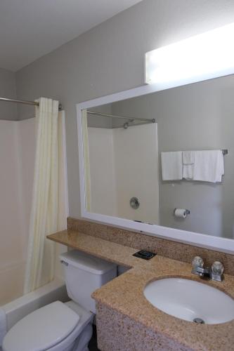 a bathroom with a sink and a toilet and a mirror at La Villita Inn in San Antonio