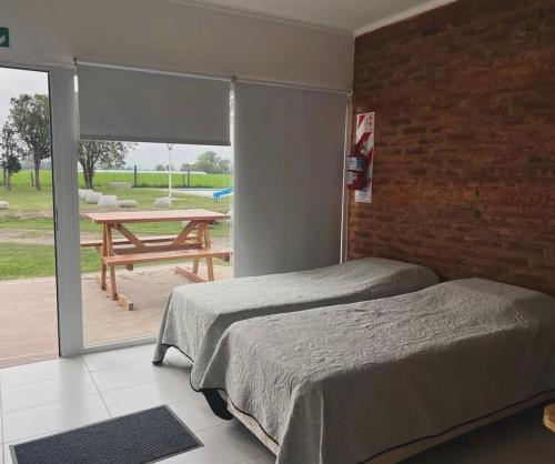 a bedroom with two beds and a patio with a table at Hotel De Campo Firmat in Firmat