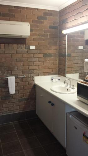 a bathroom with a sink and a brick wall at Cattleman's Rest Motor Inn in Charters Towers