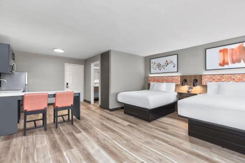 a hotel room with two beds and a kitchen at Hawthorn Extended Stay by Wyndham DFW Airport North in Irving