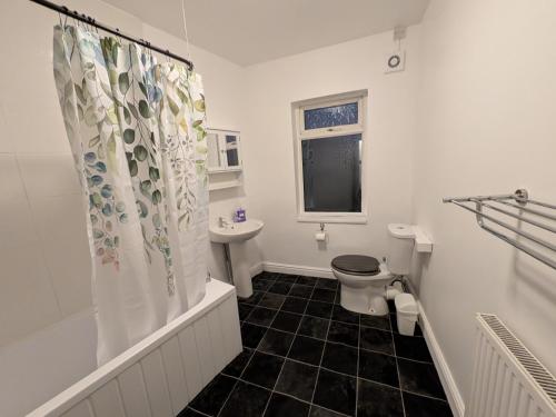 a bathroom with a toilet and a shower curtain at Stay Sleep Rest - Cranbrook in Doncaster