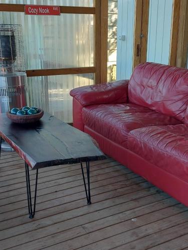 a red couch and a coffee table on a deck at The Cosy Nook in Waimate