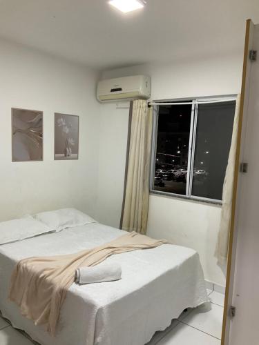 a white bed in a room with a window at Ap com 2 quartos climatizados , com fechadura eletrônica, WI-FI ,condomínio Village do bosque 3 in Imperatriz