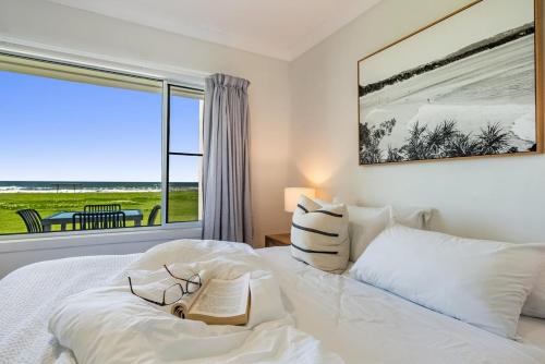 a bedroom with a large white bed with a large window at Absolute Beachfront Apartment 2B in Lennox Head