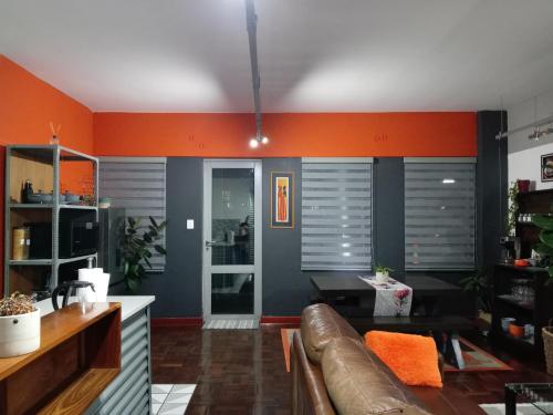 a living room with a couch and an orange wall at Warm & Luxury Stay at Maboneng with Kingbed HugeTV WiFi in Johannesburg