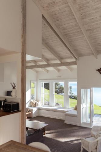 a living room with white furniture and windows at Circular Bay in Awaroa