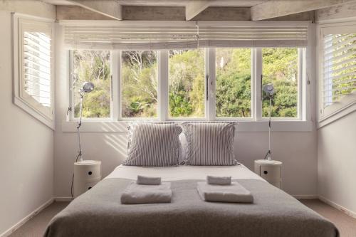a bedroom with a large bed with two windows at Circular Bay in Awaroa