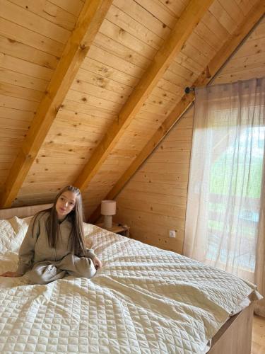a woman sitting on a bed in a attic at Camp Birch Forest in Pljevlja