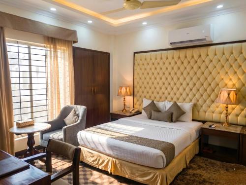 a bedroom with a bed and a desk and a chair at Imperial Swiss Garden Dhaka in Dhaka