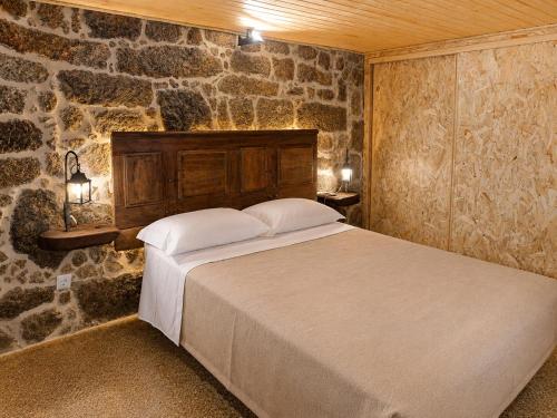 a bedroom with a bed in a stone wall at Casas da Villa- Monsanto in Monsanto