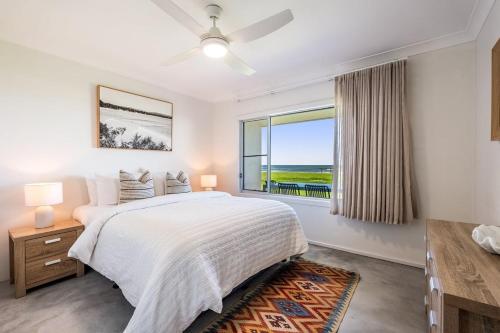 a white bedroom with a bed and a window at Absolute Beachfront Apartment 3B in Lennox Head