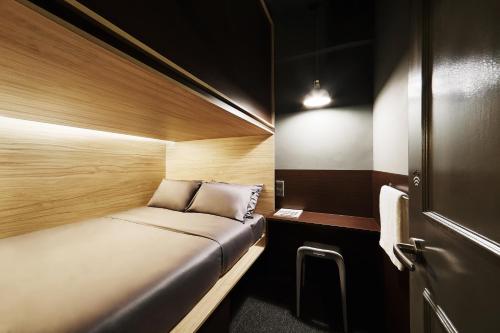 a small room with a bed and a table at The Pod at Beach Road Boutique Capsule Hotel in Singapore
