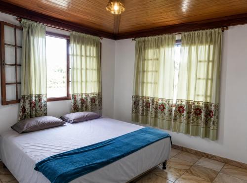 a bedroom with a bed and two windows at Sossai Hostel in Vitória