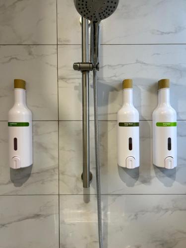 four white bottles on a wall in a bathroom at mini嵐輕旅 in Guanyin