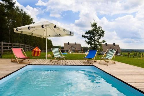 a swimming pool with chairs and an umbrella at Camping Szelągówka in Sorkwity