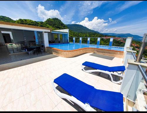 a house with a swimming pool and two blue lounge chairs at Apartamento san gil plaza in San Gil