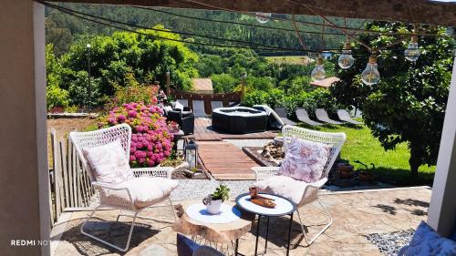 a patio with two chairs and a table and flowers at Casa Santamaria a 5min de Noia cerca de la playa in Lousame