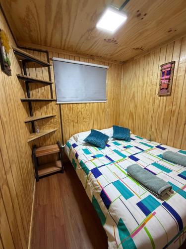 a bedroom with a bed in a wooden room at El Refugio Container in Futaleufú