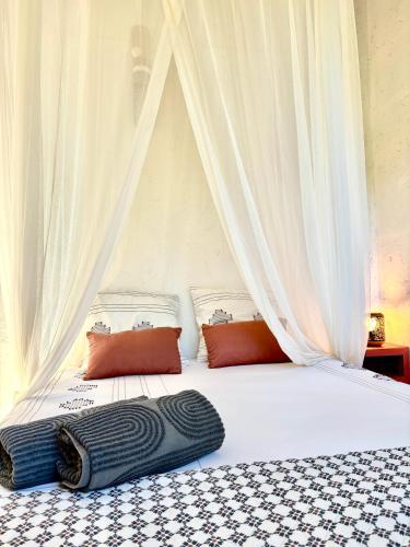 a white bed with a black blanket on it at Lodge Kara in Grand-Bourg