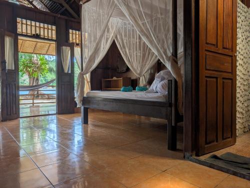 a bedroom with a bed with a canopy at Fadhila Cottages Togean Dive Resort in Katupa