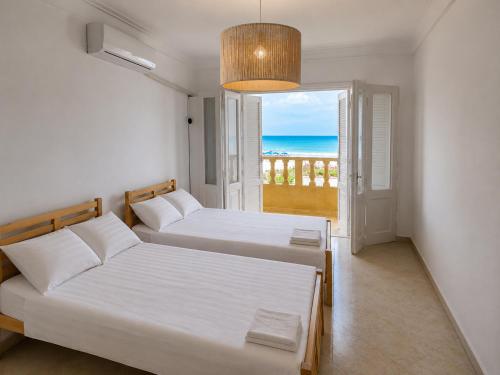 two beds in a room with a view of the ocean at فيلا غرناطه الساحل الشمالي in Dawwār al Ḩajj Aḩmad