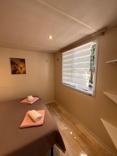 a bedroom with a bed and a window with blinds at Mobile Home Ana Mia in Biograd na Moru